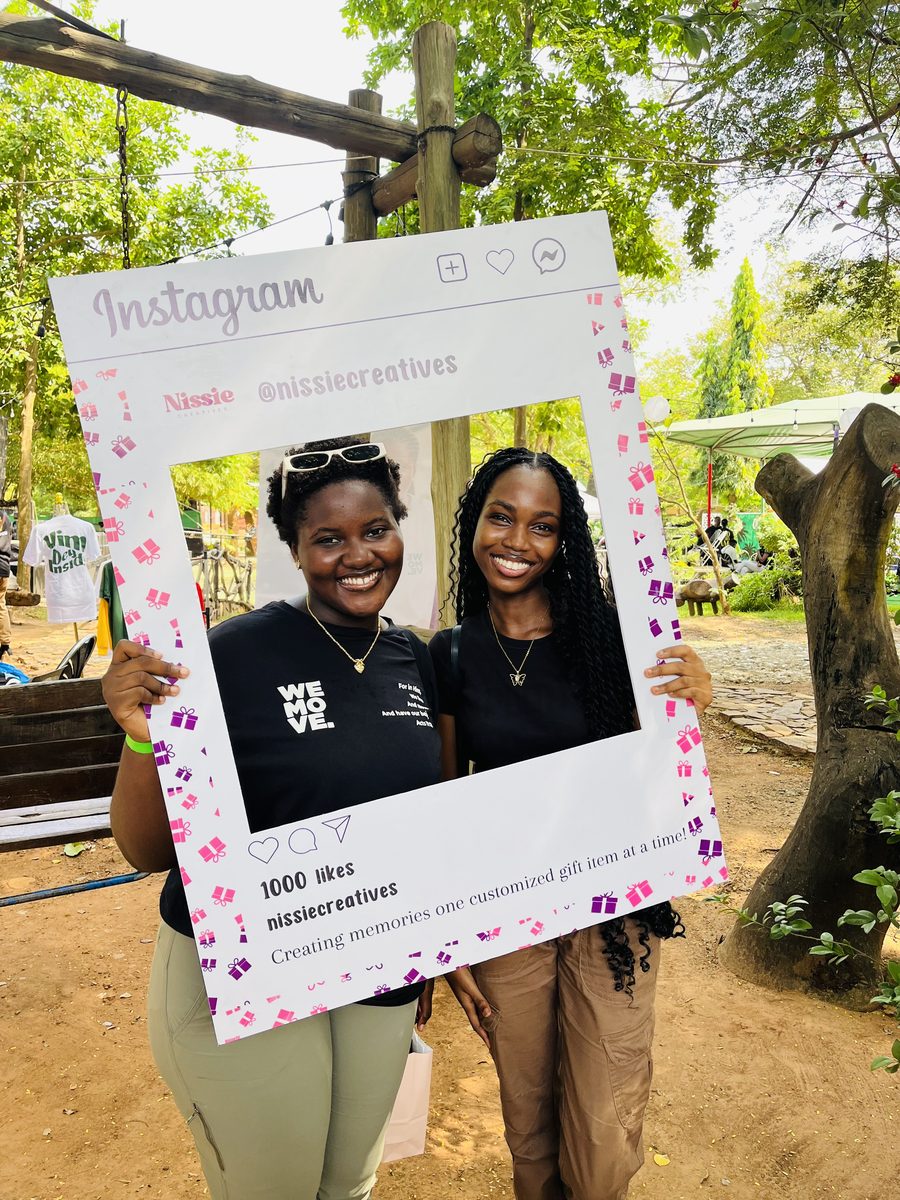 Two guests posing with a handheld Nissie photo frame at an event