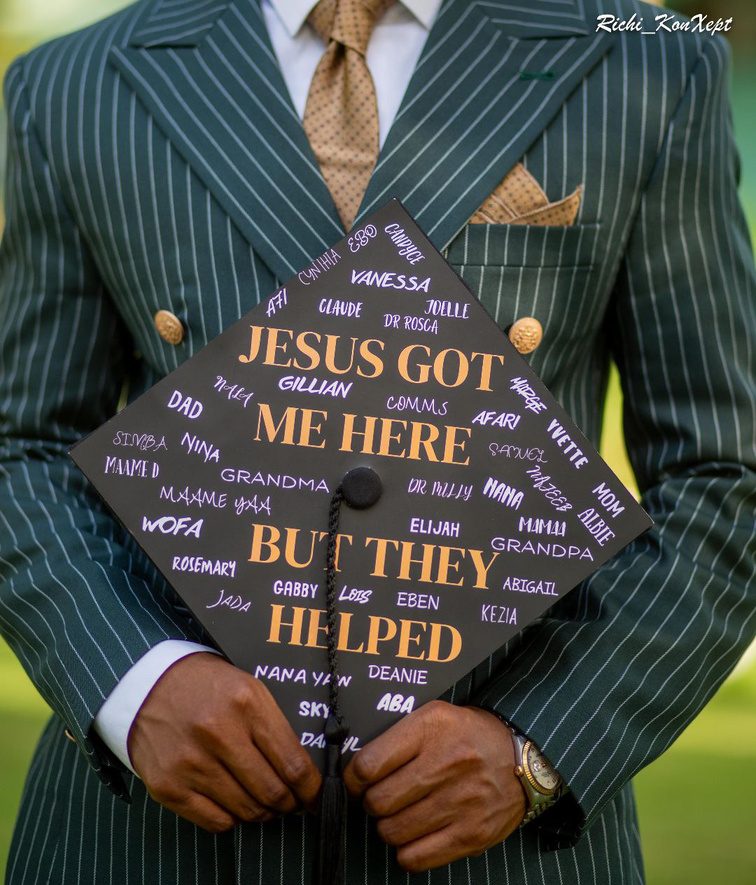 A graduate holding The Essential printed cap topper covered with supporters' names